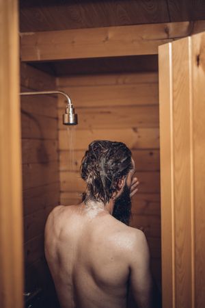 Man taking shower in wooden bathroom
