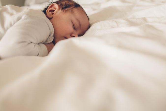 Cute newborn baby lying in bed and sleeping