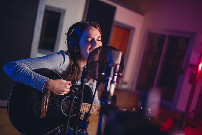 Female vocal artist singing in a recording studio with guitar
