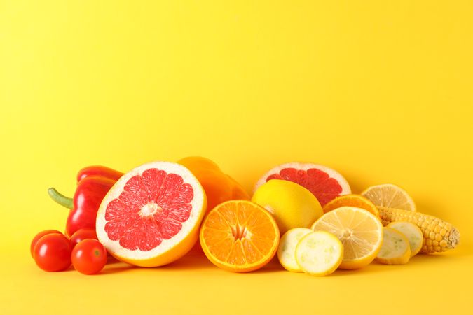 Different vegetables and fruits on yellow background, copy space