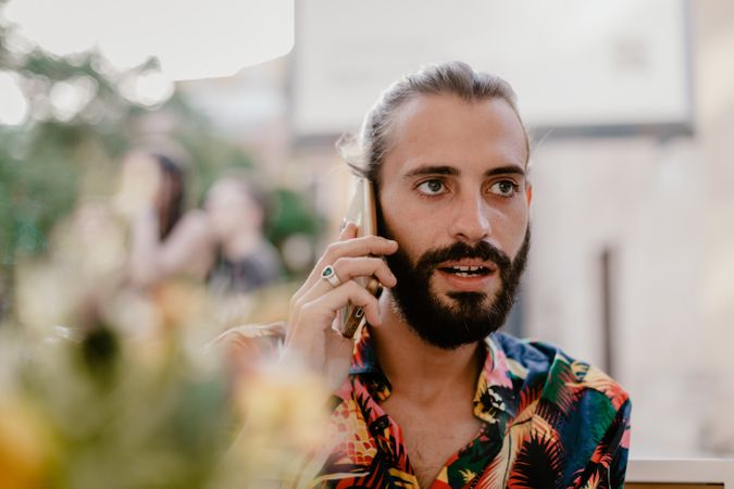 Bearded hispanic man talking on smartphone and looking away