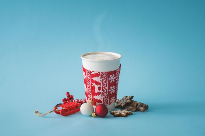 To-go cup of coffee with Christmas sleeve, decorations and cookies