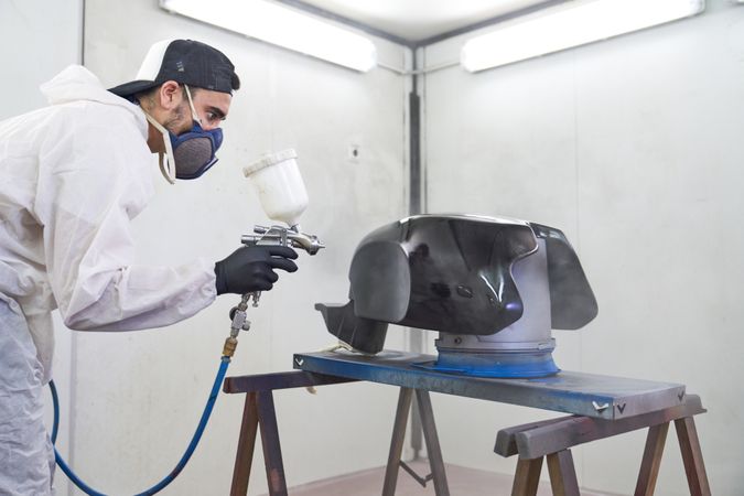 Man painting motorbike tank in workshop