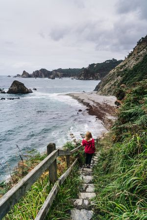 Woman walking down on stone steps leading down to foamy sea