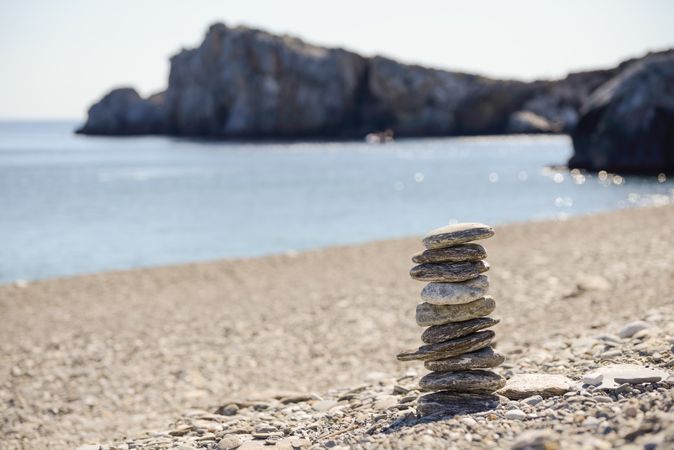 Pebbles balancing on the sandy beach with cliffs in background