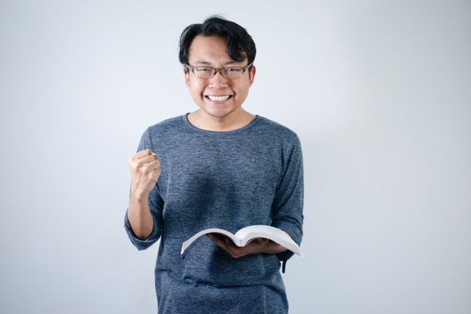 Asian student holding books and making strong gesture