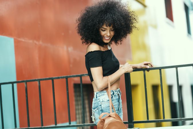 Young woman with afro hair near a modern colorful building