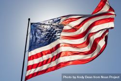 Backlit American Flag Waving In Wind Against a Deep Blue Sky 4mWxPd