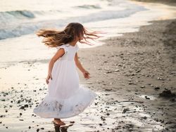 Adorable girl walking and playing on seaside at sunset
