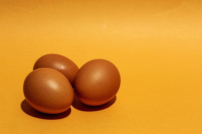 Fresh raw eggs on brown background
