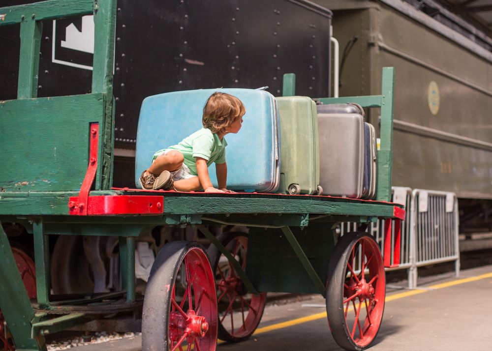 Child sitting on trailer next to suitcases