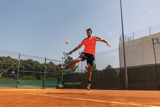 Man in sportswear playing tennis on a dirt tennis court