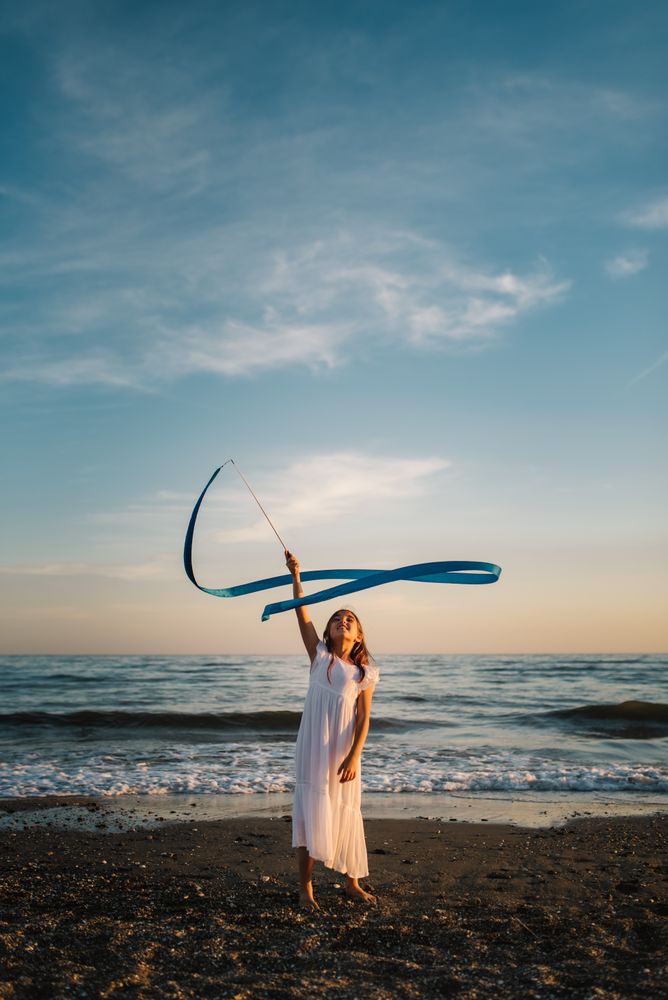 Adorable girl playing with ribbon on seaside