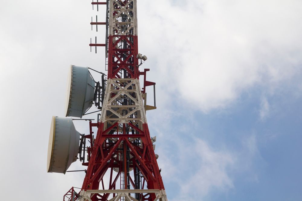Tall Communication Tower with Satellite Dishes Against a Blue Sky