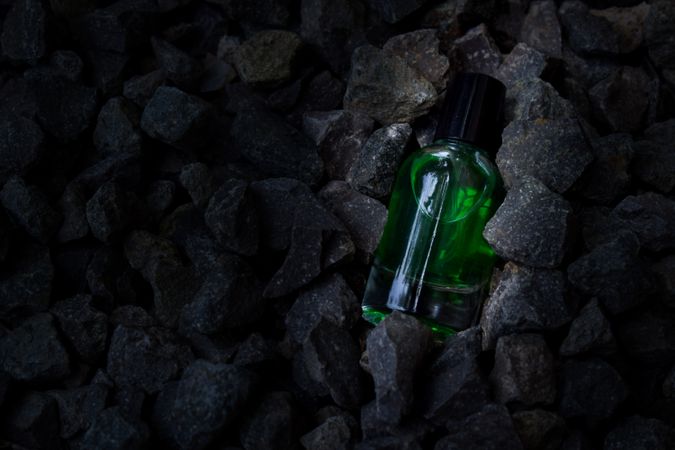 Green perfume bottle mock up laying in rocky terrain