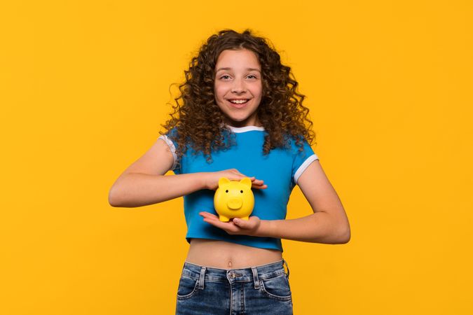 Girl holding piggy bank, emphasizing importance of saving