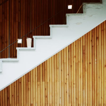 Side view of light staircase on brown wooden wall