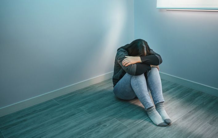 Unrecognizable desperate woman sitting sadly on floor