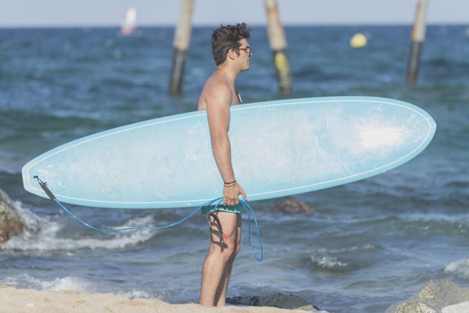 Male surfer holding surfboard approaching the ocean