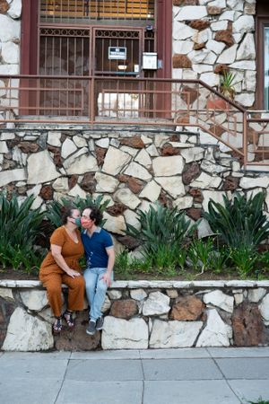 Loving man and woman sitting together outside kissing while wearing masks