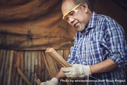 Mature male working in wood shop while wearing safety glasses 5QAVX5