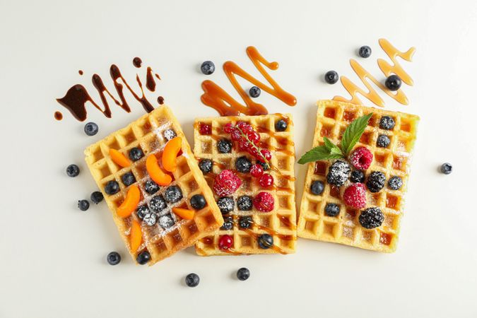 Flat lay composition with waffles and different toppings, top view