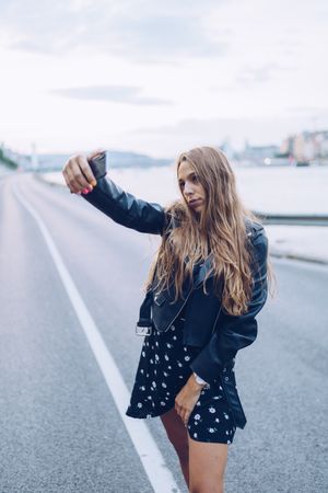 Long haired stylish woman taking selfie with smartphone