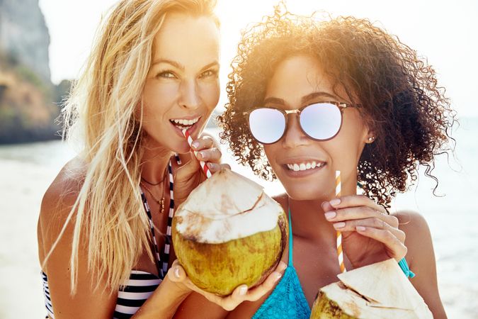 Happy women smiling with tropical cocktails outside