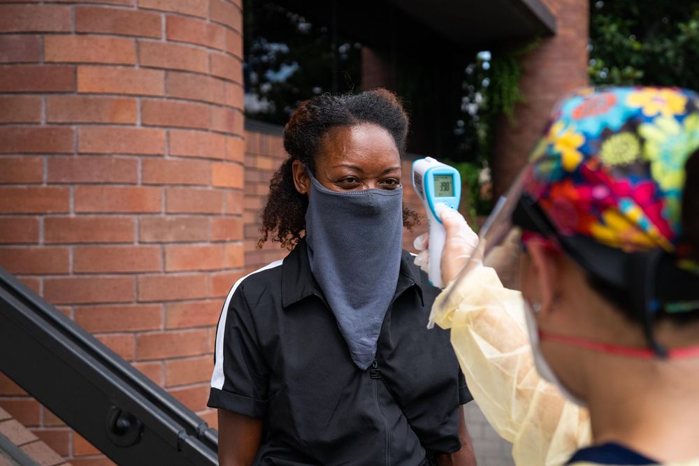 Woman standing outside having temperature taken