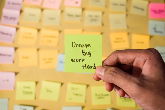 Hand hold sticky notes with words Dream Big, Work Hard