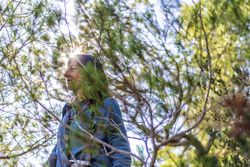 Female walking through green tree on sunny day