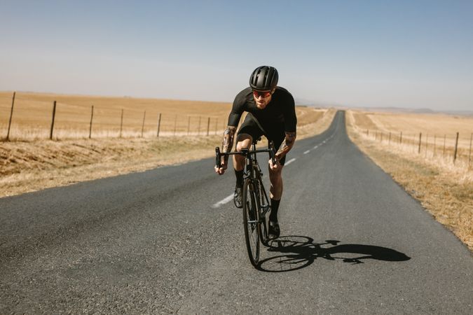 Sportsman cycling outside on long road