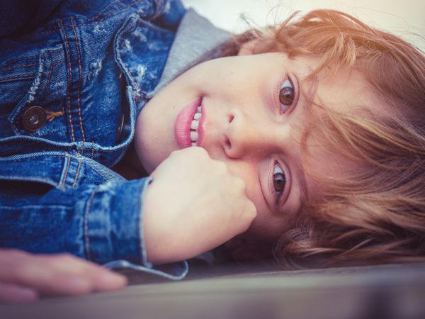 Cute child touching face and looking at camera