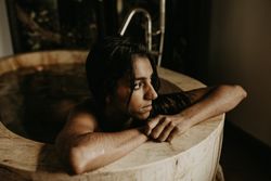 Melancholic Woman sitting and washing in bath