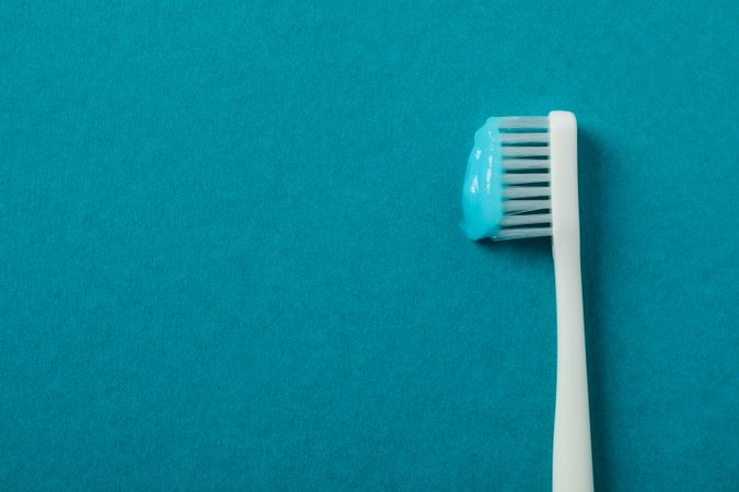 Toothbrush with toothpaste on turquoise background, space for text