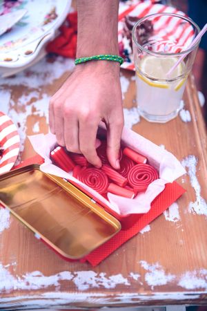 Male's hand picking candy of box at a summer party