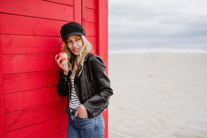 Woman eating an apple near bright wooden cabins