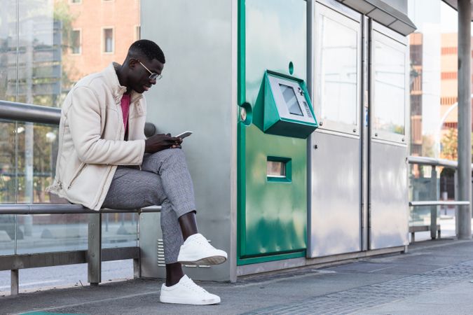Black male entrepreneur browsing smartphone on train platform