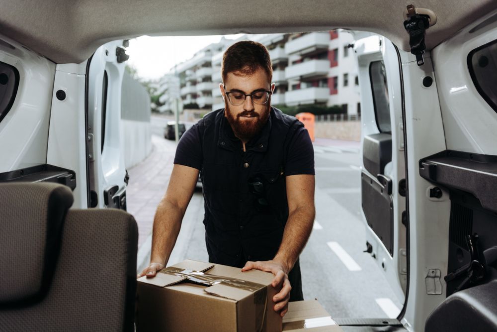 Courier taking out cartons of car for delivery completion