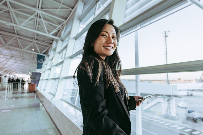 Smiling female passenger standing at airport terminal
