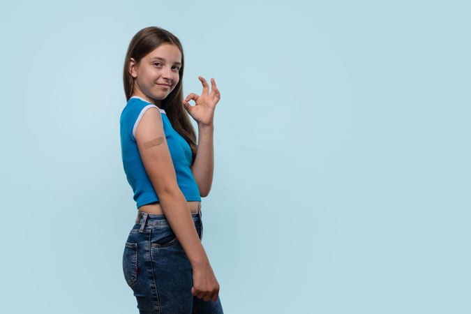 Girl making "OK" gesture while showing bandage on arm