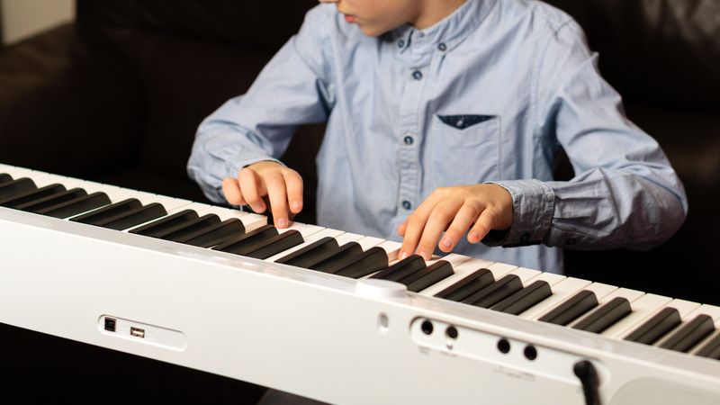 Child playing the keyboard with focused hands and fingers.