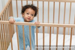 Curious baby boy standing in crib bedJ34