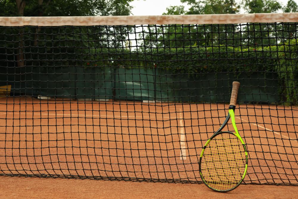 Net with tennis racket on clay court