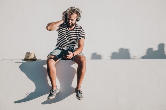 Young male sitting with smartphone and headphones