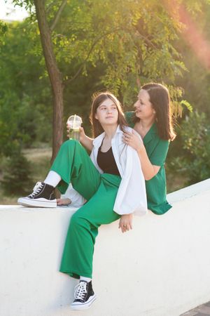 Mom and teenage daughter drink soft drinks on walk
