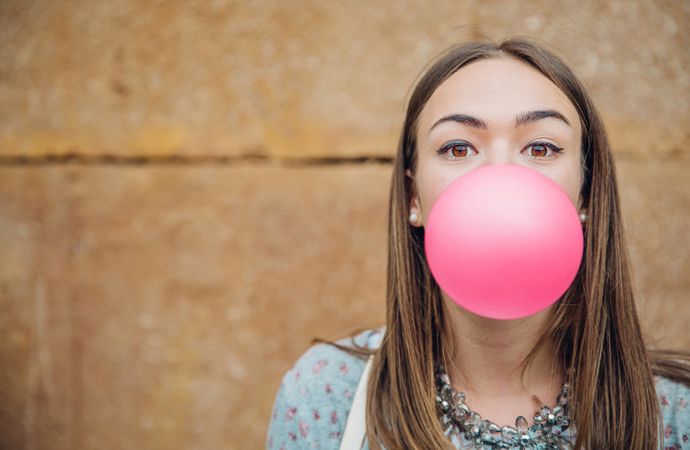 Young woman looking at camera with pink bubble gum