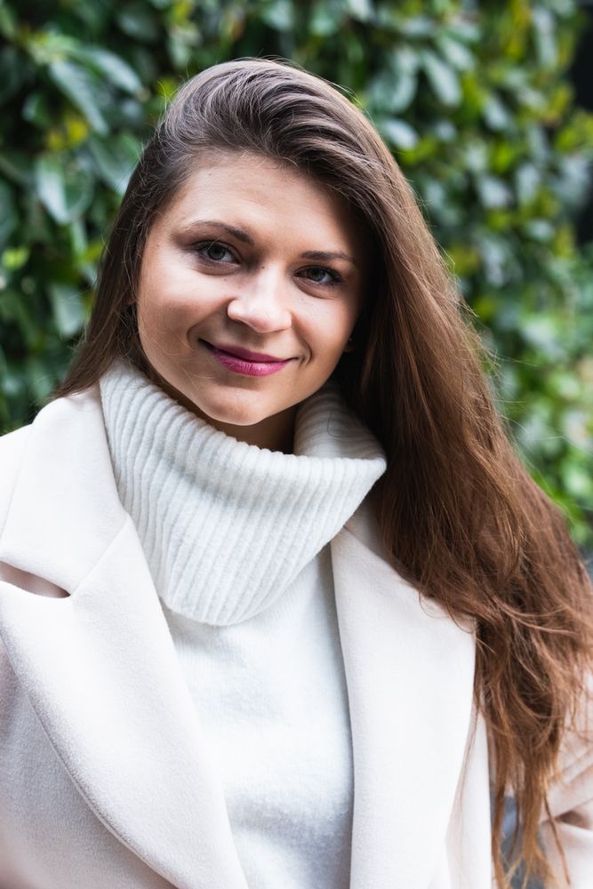 Happy stylish woman with white sweater resting in park