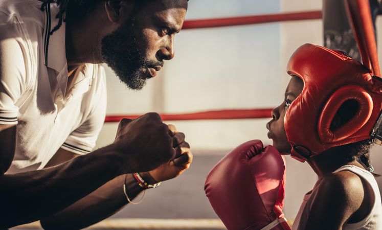 Boxing coach and girl training inside a boxing ring