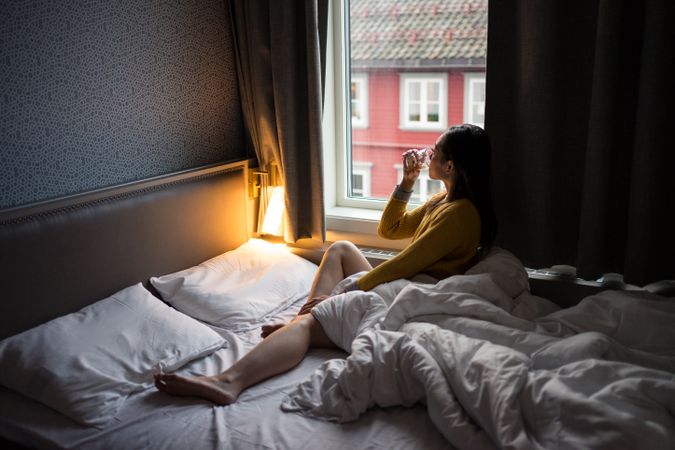 Anonymous female on vacation delighting in view in window while drinking tea in morning